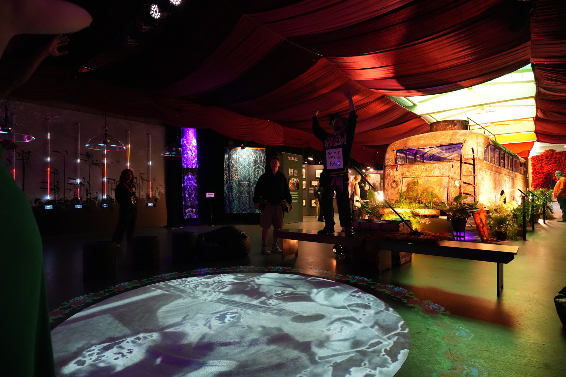 Main exhibition room with projected circular floor art and the Furthur bus beyond