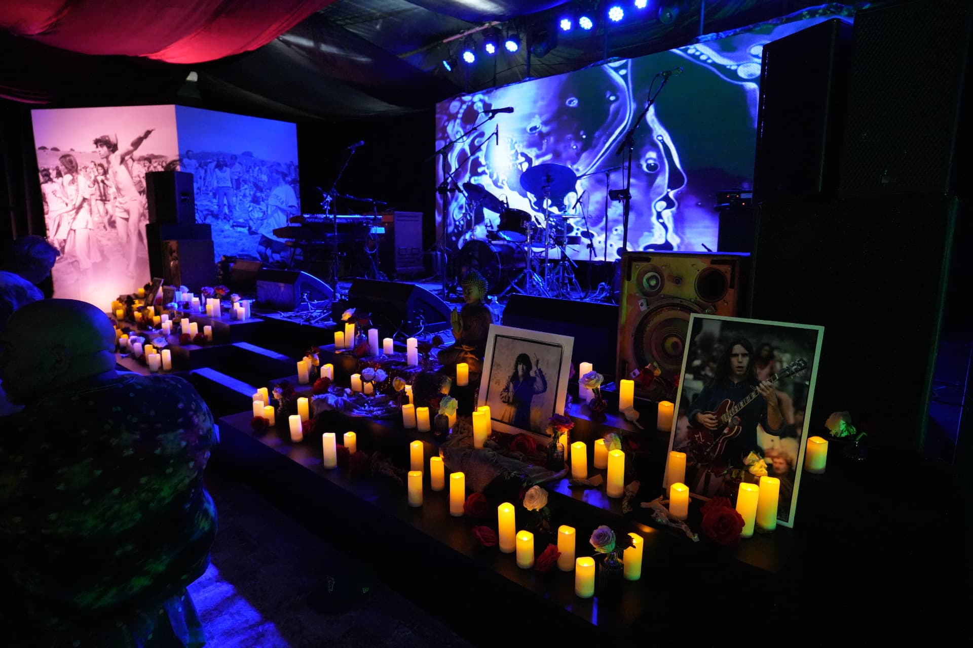 Communal altar with candles and portraits beneath projection screens